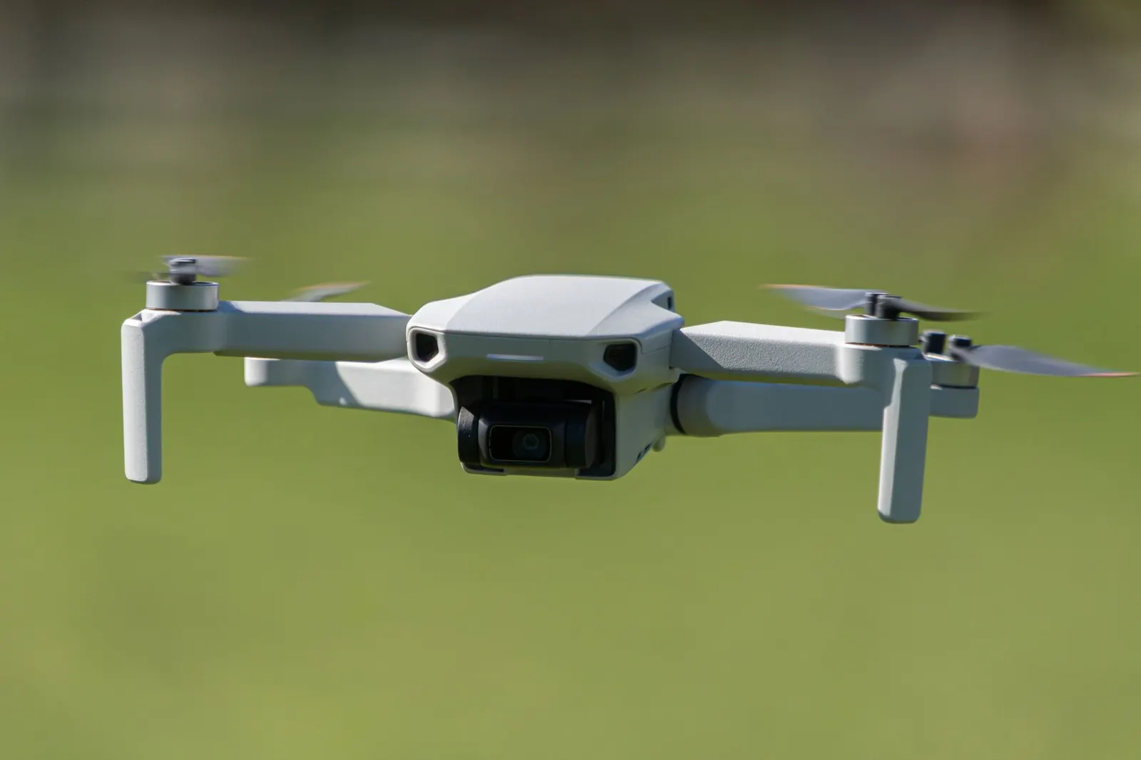 Aerial drone captured mid-flight over a lush green field in Leeds, UK.