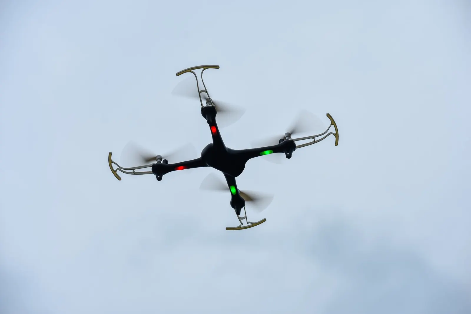 A quadcopter drone with LED lights flying in an open sky, showcasing modern technology.