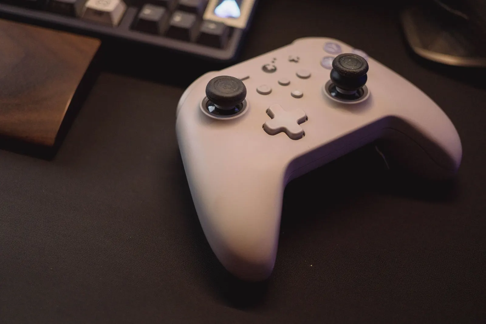 White gaming controller on a black desk setup, symbolizing modern gaming.
